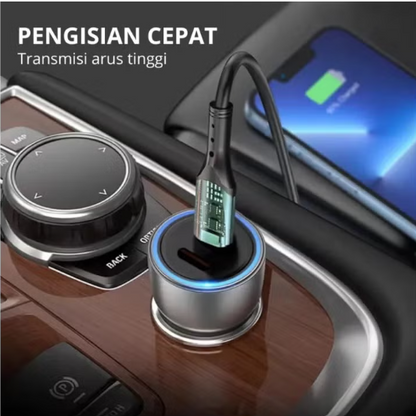 A silver and black car cigarette lighter style dual charger plugged into a car's cigarette lighter socket, with a smartphone charging in the background. Indonesian text is visible at the top left.