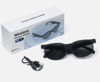 Black wireless headset glasses with dark lenses, shown next to their white retail box and a black USB charging cable on a white background.